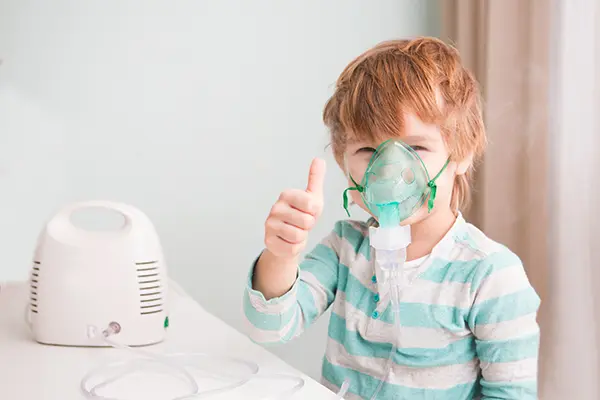 boy with oxygen mask giving a thumbs up